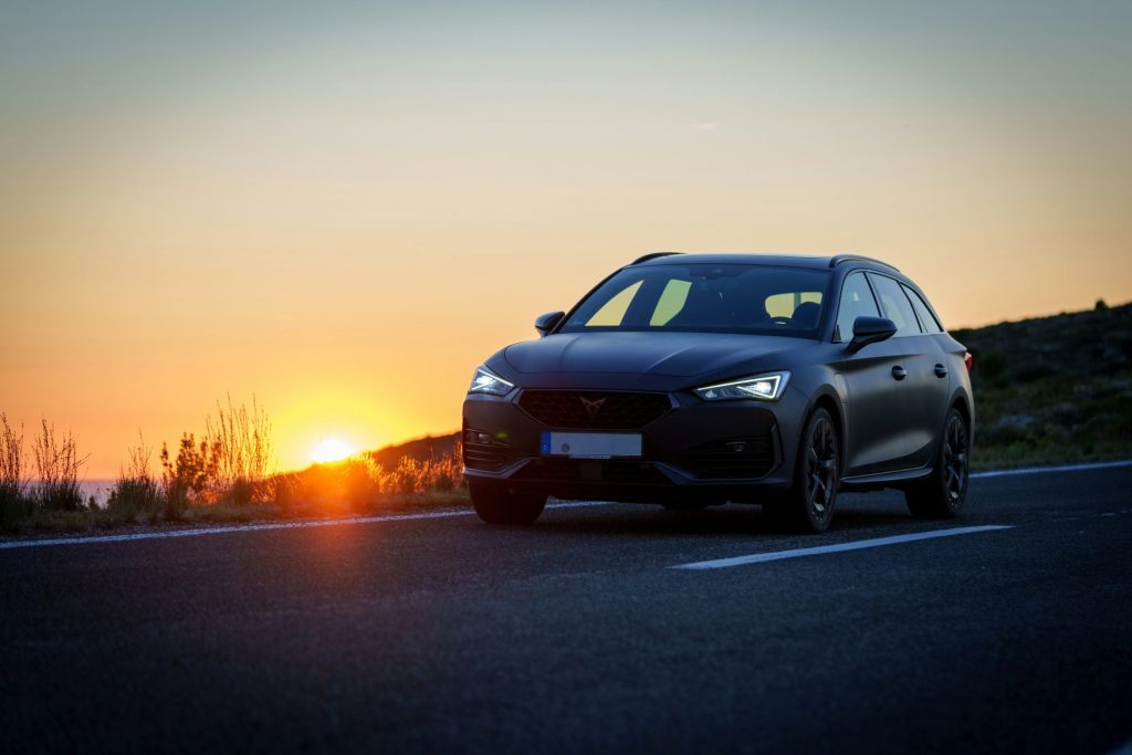 Un coche circulando por una carretera al atardecer
